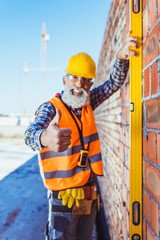 worker with spirit level showing thumb up