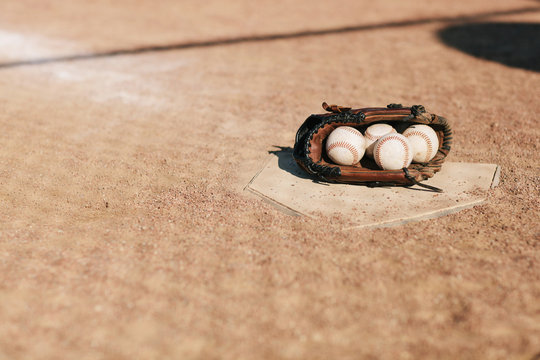Baseball glove full of baseballs on home plate