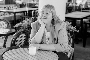 Happy overweight woman walking the city street at good day. Sunny portrait of size plus lady. Beautiful overweight woman standing on city street