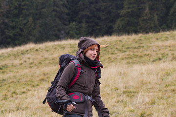 Naklejka na ściany i meble Female hiker with backpack walking on the mountains roads, autumn forest background 