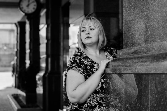 Happy overweight woman walking the city street at good day. Sunny portrait of size plus lady. Beautiful overweight woman standing on city street