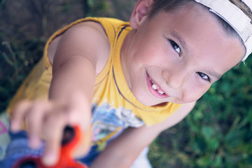 Young schoolboy holding popular fidget spinner toy - close up portrait. Happy smiling child playing...