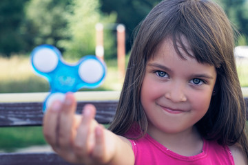 Young schoolgirl holding popular fidget spinner toy - close up portrait.