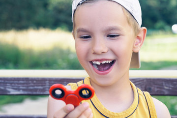 Young schoolboy holding popular fidget spinner toy - close up portrait. Happy smiling child playing...