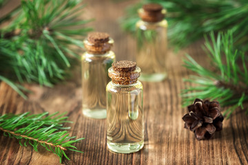 Essential oil of pine and spruce in small glass bottles on a wooden background. Soft focus.