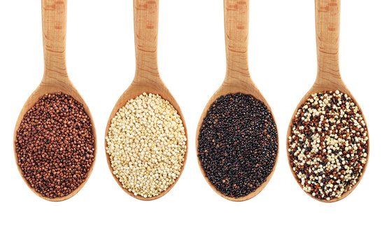 Black, red and white quinoa grains on wooden spoon.