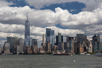 Naklejka premium Miejski Nowy Jork Amerykański krajobraz z oceanu (wśród wody) z drapaczami chmur i błękitne niebo z kontrastowymi chmurami na tle