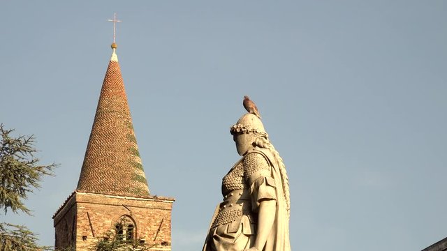ancient statue with pidgeon on head near belfry