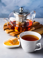 Cup of red tea rooibos and honey with glass teapot on blue