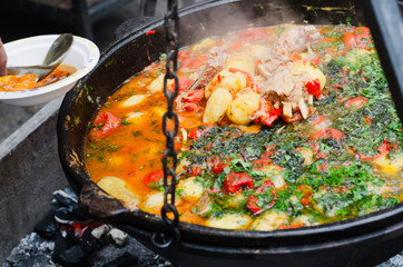 Vegetables with meat stewed in a cauldron. Street food, food festival.