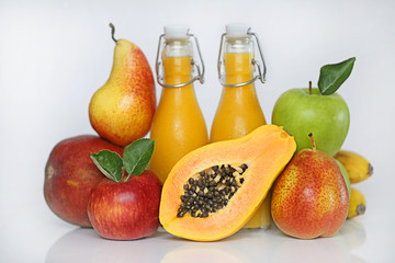 Smoothies tropical mix. smoothies from mango, banana, papaya, pear, red and green apples in transparent glass bottles and fresh fruit on a light background. Super food concept