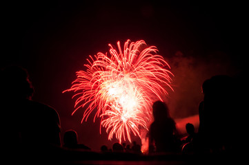 red fireworks with silhouettes of spectators  in foreground