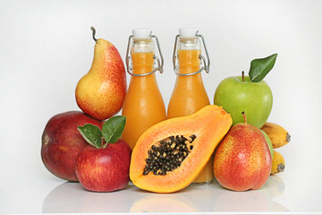 Smoothies tropical mix. Orange smoothies from mango, banana, papaya, pear, red and green apples in transparent glass bottles and fresh fruit on a light background. Super food concept