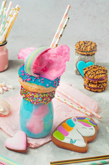 Freak shake topping with donut and cotton candy over grey background