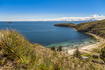 Fototapeta premium Blue water and coast of Titicaca lake, boats, walking people and bolivian village at Incas Island of the Sun, Bolivia, south America