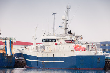 Naklejka premium Blue white trawler ship stands moored in port