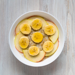 Healthy Breakfast in the morning - oatmeal with fruit and honey, slices of apples and bananas, caramel syrup.  Top view.