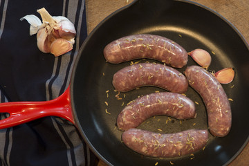 Uncooked sausages in a cast iron frying pan