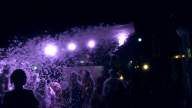 summer, night, foam party, in the rays of soffits, foam poured into the dancing people