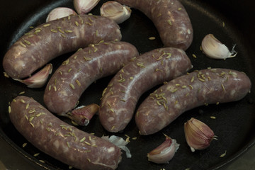 Uncooked sausages in a cast iron frying pan