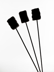 Silhouettes of marshmallows on wooden skewer sticks, isolated on white background