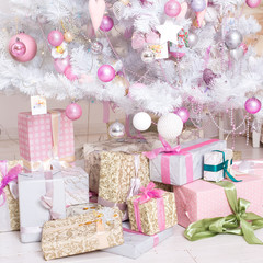 Giftboxes, pink and white christmas decorations balls hanging on a decorative white christmas tree.Pink and white christmas decorations balls hanging on a decorative white christmas tree.
