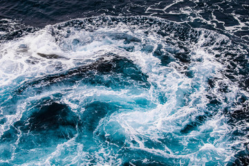 vertiginous, swirling foamy water waves at the ocean photographed from above