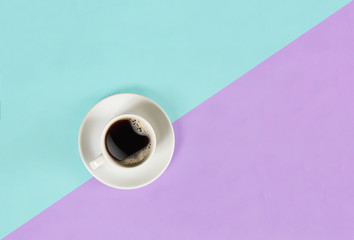 A cup of black coffee on blue and lilac background. View from above.