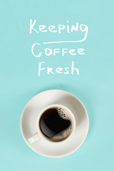 Top view of cup of black coffee and Keeping coffee fresh lettering isolated on blue background