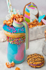 Freak shake topping with donut, popcorn over grey background