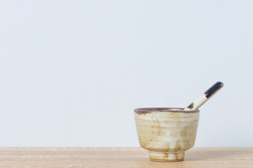 Ceramic bowl and ceramic spoon on wooden table