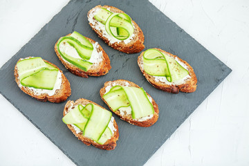Snacks with cheese feta and cucumber on shale board. The concept of food and vegetarianism.
