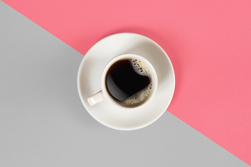 A cup of black coffee on gray and pink background. View from above.
