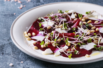 Vegetarian beetroot carpaccio salads with olive oil, goat cheese, pine nuts and sprouts in white...