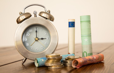 clock with money on a wooden background