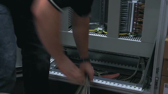 A person works on a server station by pulling out and arranging the wiring. Close up.