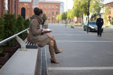 Fototapeta na wymiar young woman sitting on a bench with a book in her hands, looking away