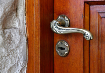 Closed door of a family home. Close-up of the lock of a classic entrance door  of wooden and handle of brass.