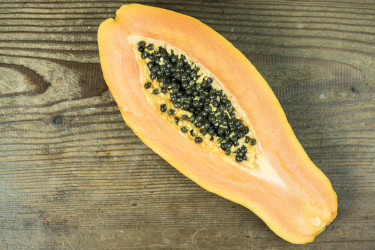 High angle view of papaya cut in half against wooden background