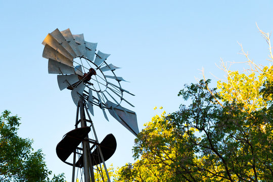 Windmill in a beautiful day of summer in an countryside. The blue clear sky and the foliage green of trees.