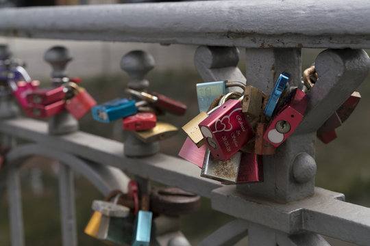 Colorful padlocks fixed to metal balustrade as symbol of love