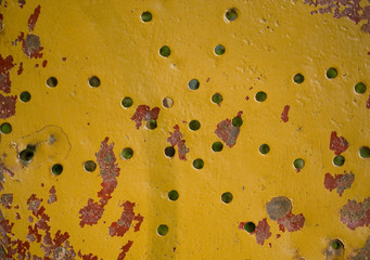 texture: metal garden chair with small round holes to slide the water, yellow and red paint, it is ruined because of weathering, creating rust, Italy