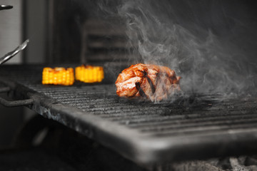 Beefsteak with corn grilling on barbeque stove with tasty smoke