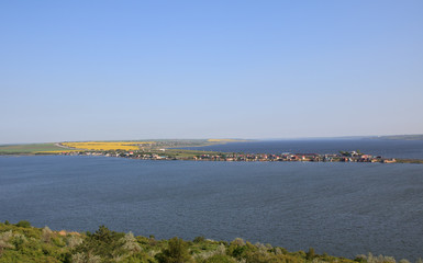panoramic view on the valley with yellow field, road, lake and houses