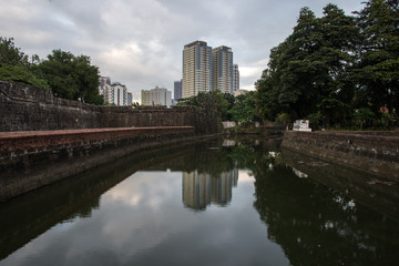 View of the canal with water against the backdrop of the cityscape with trees and buildings. 