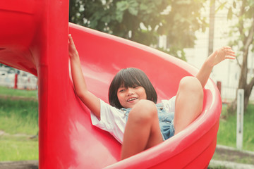 Fototapeta na wymiar Cute asian little girl playing slider in the playground in park