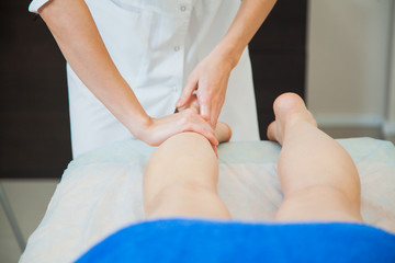 Beautician masseuse massaging female legs, bodycare concept