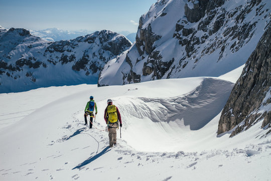 two alpinists walking along a ridge on a glacier