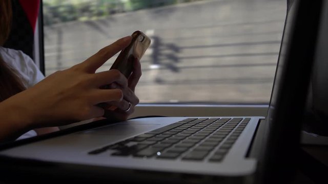 4K Businesswoman working with computer in train travel. Asian young woman sit down near the window in higth speed rail checks her phone and computer. Girl Works with Laptop. Programming. Student-Dan