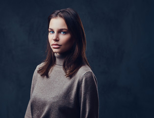 A woman dressed in a long neck brown jacket.